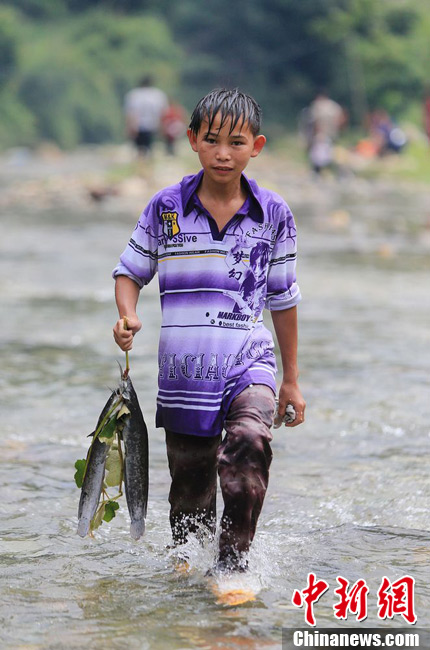 圖為7月9日，一名男孩在鬧魚節(jié)活動中抓到了兩條魚。譚凱興 攝