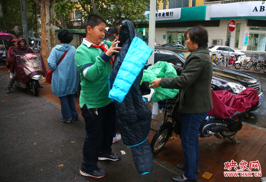 學(xué)校門口，家長給孩子帶來了御寒的厚衣服。