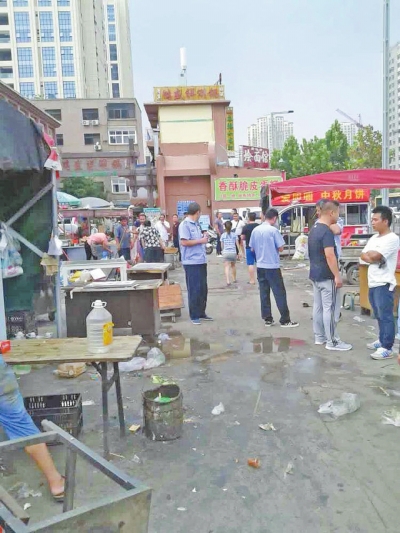 昨天，執(zhí)法人員在京廣路長江路口整治“僵尸圍擋”及圍擋內(nèi)的攤販。
