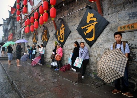 　4月29日上午11時(shí)20分，一些游客和古城當(dāng)?shù)氐木用穸阍谝粋€(gè)酒吧的屋檐下避雨。這些當(dāng)?shù)鼐用褚詾橛慰团恼罩\生，一場(chǎng)降雨讓他們的生意更加清淡。