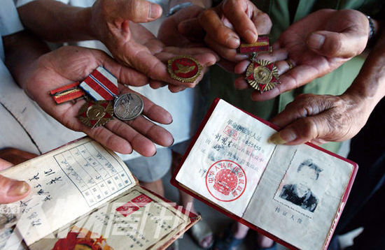 幾位志愿軍老兵展示自己的立功證、傷殘軍人證與勛章