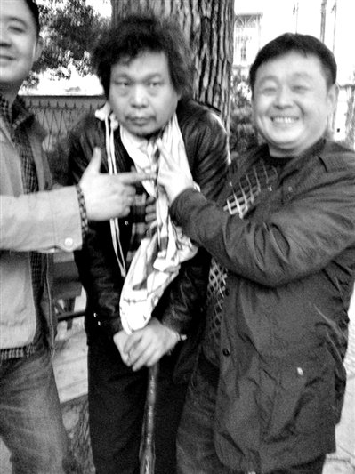 兩名接訪人員與患有癌癥的訪民段新德合影時(shí)，面帶笑容擺出勝利的手勢(shì)。