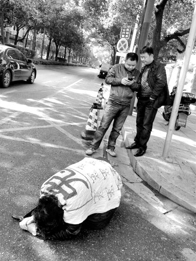 兩名接訪人員與患有癌癥的訪民段新德合影時(shí)，在拍照時(shí)查看手機(jī)。