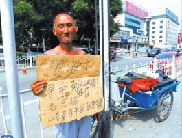 老人舉著牌子在路邊等候失主。京華時報記者譚青攝