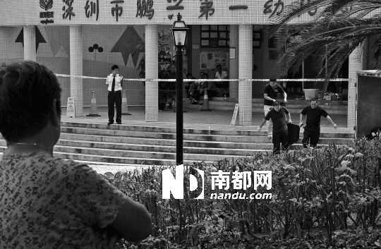 →7月19日，鵬興花園第一幼兒園門(mén)前，民警在現(xiàn)場(chǎng)進(jìn)行完勘查取證后，園長(zhǎng)和保安的尸體被運(yùn)走。南都記者 徐文閣 攝