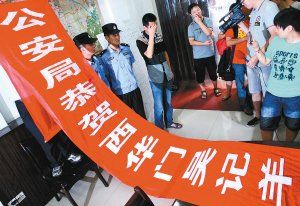 面對警方收繳的條幅，老板楊某也不好意思地用手遮擋臉