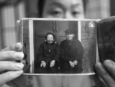 圖為孫女拿出兩位老人上世紀(jì)80年代在家門口的合影給記者看。記者楊濤 攝