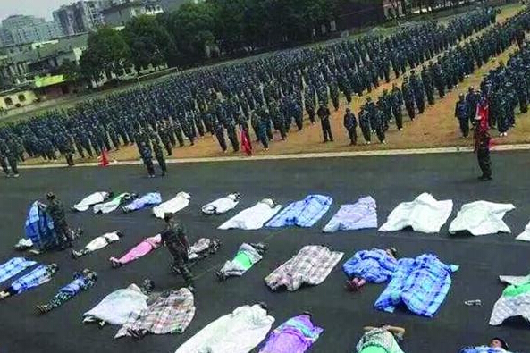 20多名女生躺在瀝青跑道上，身上嚴(yán)嚴(yán)實(shí)實(shí)地裹著棉被，接受太陽的照曬。