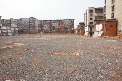 為降塵，旮旯王村拆遷后裸露的地面上鋪了一層石子。