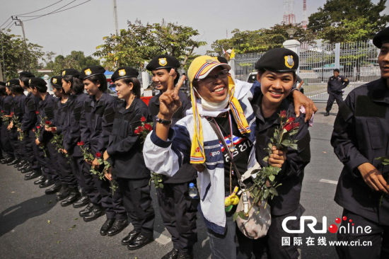 2013年12月03日,曼谷總理府與曼谷警署允許反政府示威民眾進入,雙方進入暫時“停戰(zhàn)”狀態(tài)迎接泰王生日。曼谷警察總署,女警們手持鮮花送給反政府示威民眾。圖片來源:Manish Swarup/東方IC