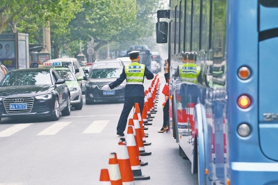 省人民醫(yī)院南門的路中間擺放反光錐，交警示意由西向東車輛從前方繞行。