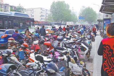 省人民醫(yī)院北門，路邊的公交站牌處停滿非機(jī)動車，上、下客只能在快車道上。