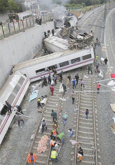 24日，救援人員在西班牙列車脫軌現(xiàn)場。一節(jié)車廂被強(qiáng)大的慣性拋上鐵道邊的高臺(tái)。