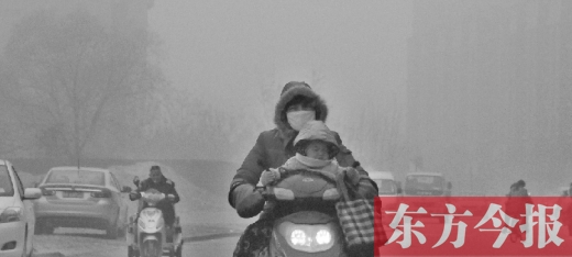 12月8日，鄭州市未來路上，一位市民帶著孩子在霧中騎行