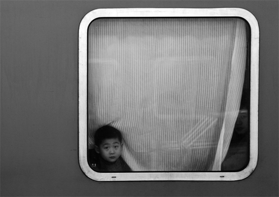 一個(gè)孩子把頭伸向窗外，他想再看送別的親人一眼