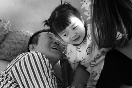 病床前李剛父女倆說著“悄悄話”，幸福的氣氛洋溢在病房中
