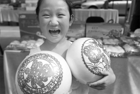 在2013河南食品安全宣傳周活動現(xiàn)場，一個(gè)小女孩抱著參展的特色大饅頭樂開了花