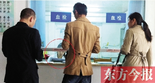 昨日，鄭州市二七區(qū)疾控中心辦證大廳，血檢窗口內(nèi)一名女工作人員，邊接受辦證者咨詢邊看報紙