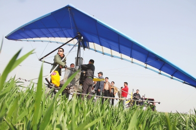 　　4月12日，在武陟縣北郭鄉(xiāng)韓余村，一架三角翼動(dòng)力滑翔機(jī)在對(duì)小麥進(jìn)行農(nóng)藥噴灑作業(yè)。為提升農(nóng)業(yè)生產(chǎn)的