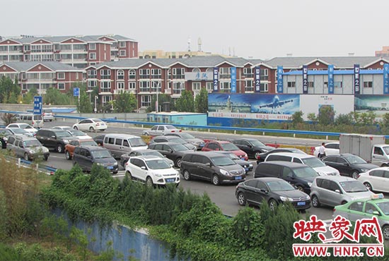 記者看到鄭州機(jī)場(chǎng)收費(fèi)站口車輛排隊(duì)，與此形成鮮明對(duì)比的是，路的對(duì)面（另一半幅）卻車輛較少，通行順暢。