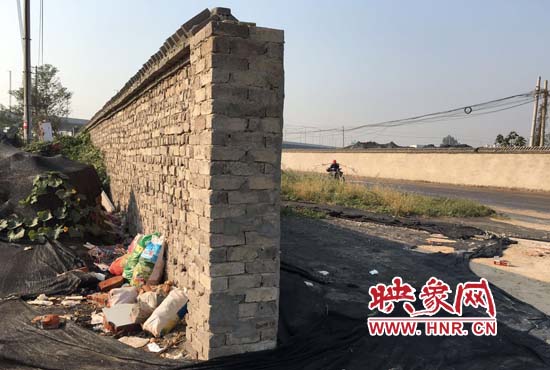 一墻之隔，一邊是道路，一邊是垃圾和荒草，市民質(zhì)疑其為遮羞墻。