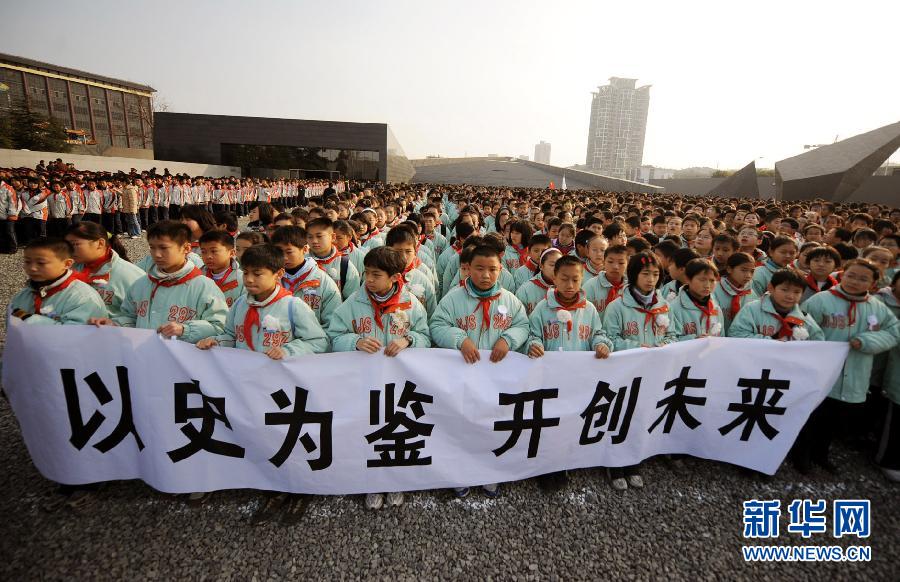 ，南京市小學(xué)生代表手持“以史為鑒 開創(chuàng)未來”的橫幅在南京大屠殺遇難同胞紀(jì)念館集會(huì)廣場參加悼念儀式?！? width=
