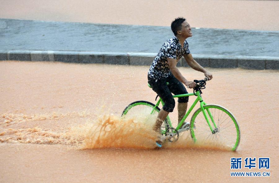 5月11日，一名行人在深圳街頭冒雨騎行。
