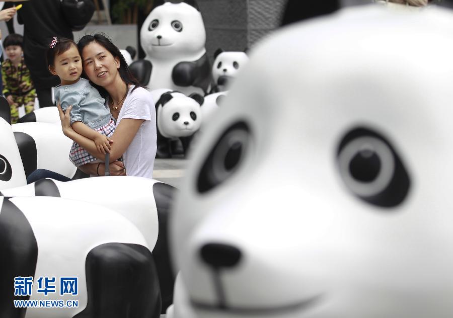 6月2日，一位家長(zhǎng)帶著孩子在上海街頭和大熊貓模型合影。