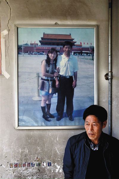 11月14日，承德市平泉縣，潘小梅父母的家，潘小梅父親靠在墻上，身后掛著數年前他和潘小梅在北京的合影照片。新京報記者