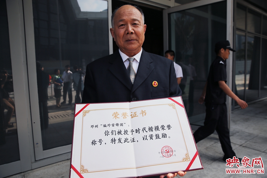 河南鄧州“編外雷鋒團”團長宋清梅向眾多記者展示中宣部授予的“時代楷?！睒s譽證書。