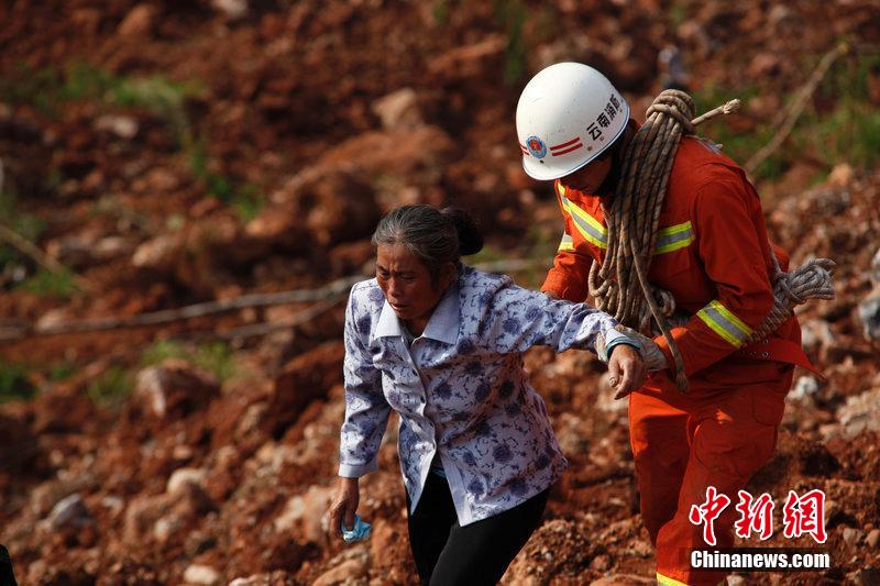 一位消防戰(zhàn)士將一位失去親人的老人扶離滑坡點。