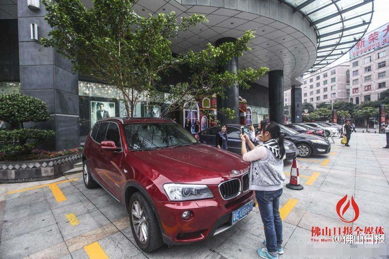 一輛停在停車位上的寶馬轎車，被墜落的樹枝砸中，樹枝徑直插入車內(nèi)，現(xiàn)場引發(fā)不少市民圍觀拍照。