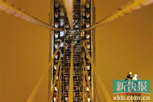 截至今日零時(shí)，男子仍未有下橋舉動(dòng)。圖為公安和消防人員乘消防云梯在高空上和男子交談。