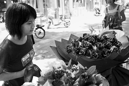 鄭州市農(nóng)業(yè)路一家花店擺放的玫瑰花吸引著一位過往女孩。