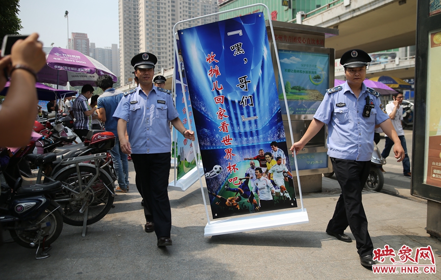 7月2日上午，鄭州市紫荊山地鐵站出入口，執(zhí)法人員抬著寫有勸導(dǎo)語的宣傳板，前往占道經(jīng)營攤位“圍觀執(zhí)法”